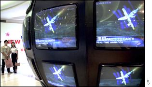 Shoppers watch television screens in Bangkok