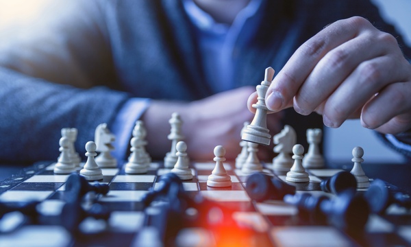 image shows a chess board with someone moving a piece