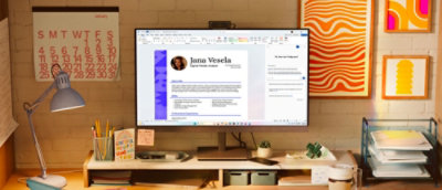 Espace de travail de bureau avec un grand moniteur affichant une interface de profil professionnel, entouré de fournitures de bureau et de décorations murales.