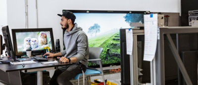 Seorang pria duduk di depan meja dan bekerja menggunakan desktop.