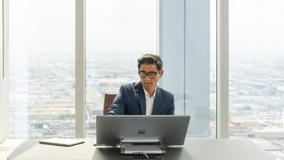 Una persona utiliza un monitor en un gran escritorio con el paisaje de la ciudad detrás