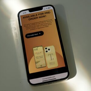 A Trump Mobile webpage displayed on a phone screen describes the Trump T1 phone as being "MADE IN THE USA," in all capital letters.