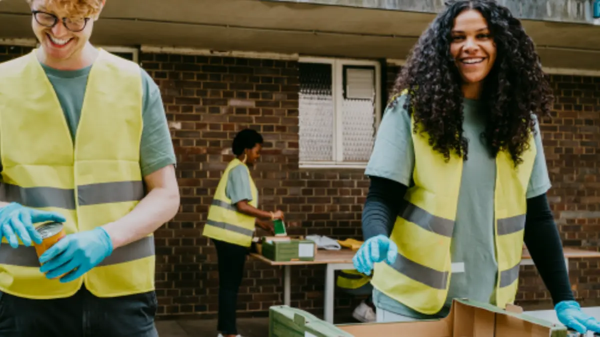 Volunteers wearing safety vests and gloves sorting food items at a community service event.