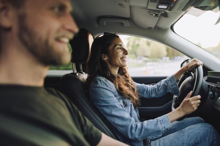 Smiling woman driving car while sitting with man