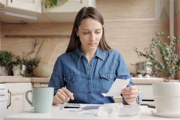 a person sitting at a kitchen table with a cup of coffee and a piece of paper