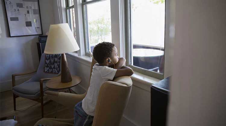 Niño mirando por una ventana.