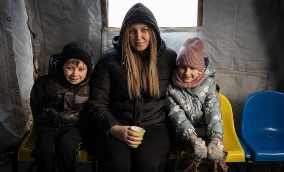 Kateryna and her two children warm up at a heating point and use rhe available electricity to charge their devices. 