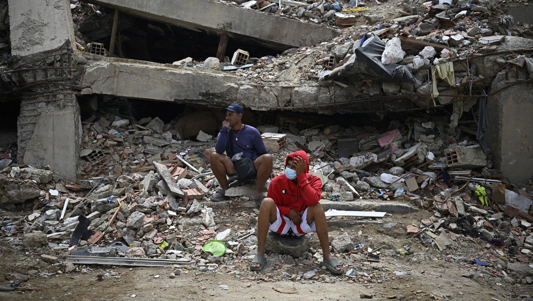 Residents sit amid the rubble of a residential building that collapsed following the two powerful earthquakes in June, in Caraballeda, Venezuela, on July 20, 2026. (Federico Parra/AFP via Getty Images)