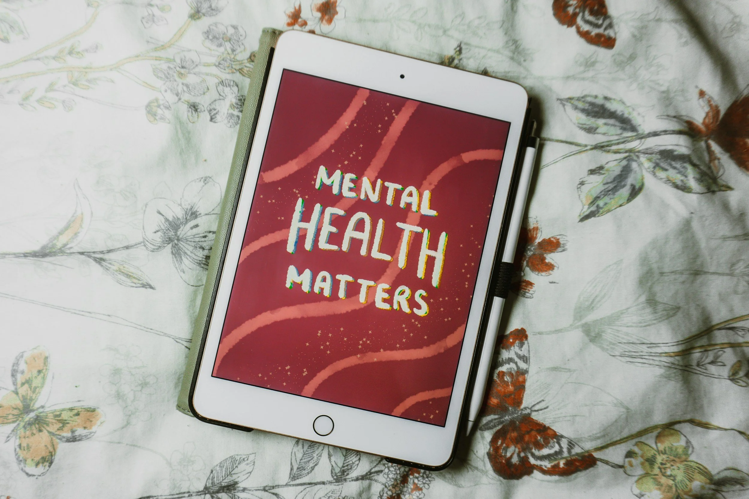 Tablet on floral bedspread displaying the text 'Mental Health Matters'.
