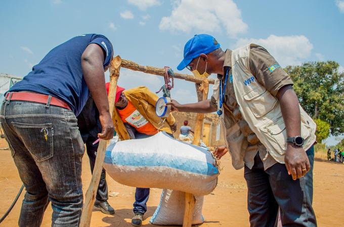 WFP staff Pennias Mulauzi helping farmers weigh crops for the market WFP_Paul MboshyaJR