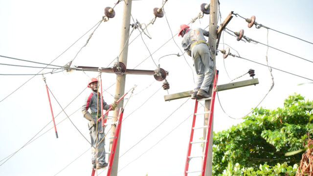 Electricians on ladders working on city power lines