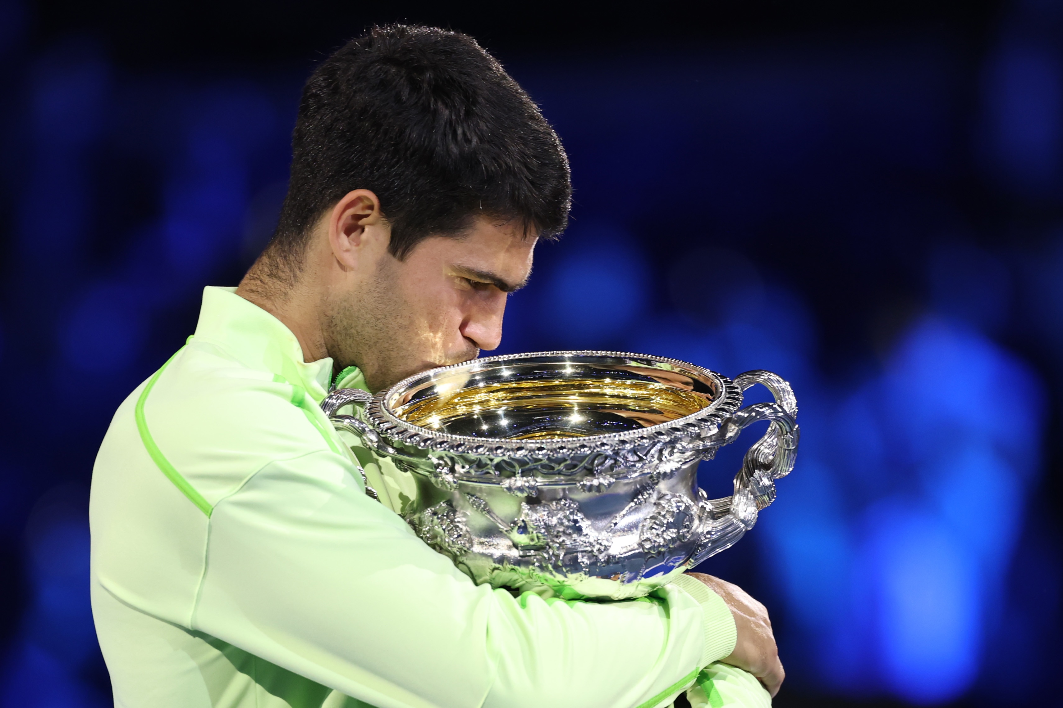 Carlos Alcaraz hugs and kisses the Australian Open trophy.