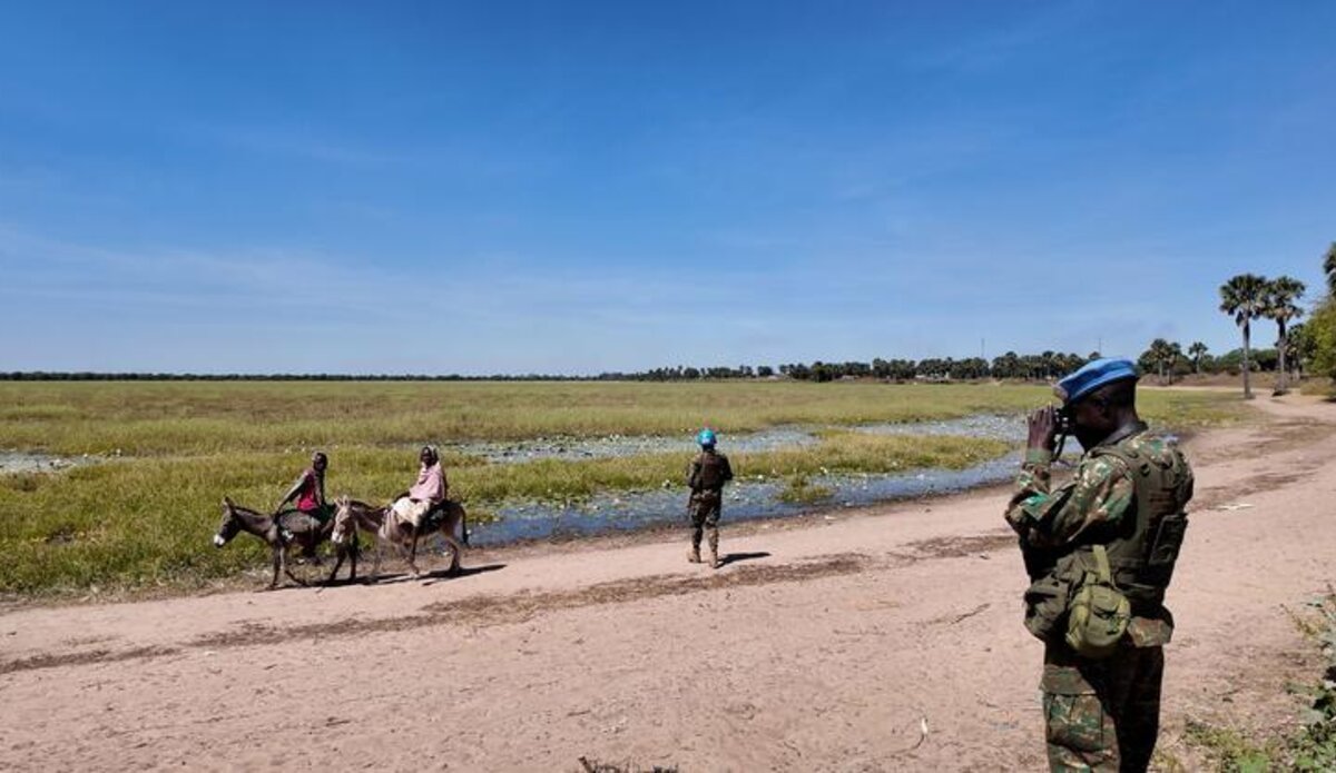Peacekeepers walk along a dirt road