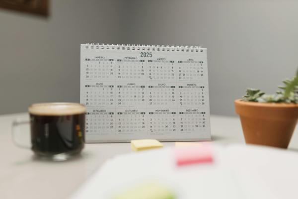 Desk calendar beside a coffee cup and small potted plants