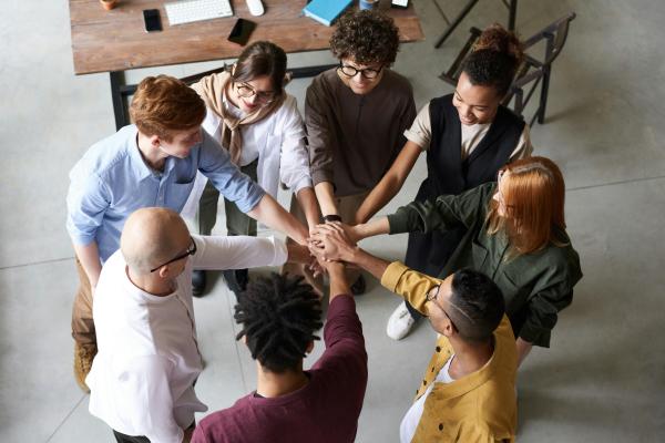Diverse team standing in a circle with hands stacked together in collaboration