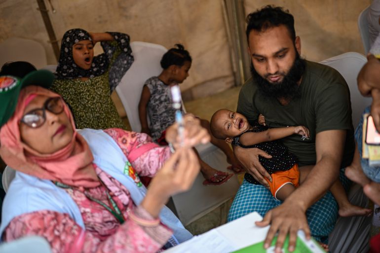 A healthcare worker prepares a measles vaccine while a father holds his young daughter at a vaccination center in Dhaka, Bangladesh, Sunday, April 12, 2026. (AP Photo/Mahmud Hossain Opu)