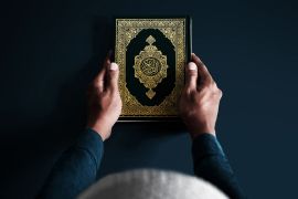 Man holding holy book on dark background