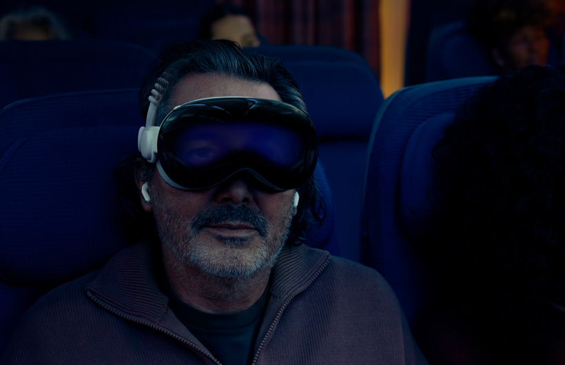 Personne assise dans un avion, portant un Apple Vision Pro avec un bandeau tissé à sangle double