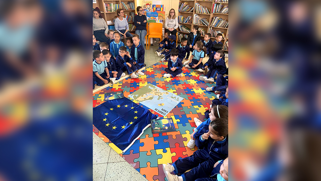 Children gathered around the map and the flag of the European Union in a classroom in a Maltese primary school
