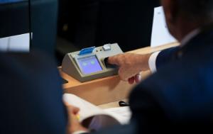 A member of the European Parliament is voting introducing his hand in the voting machine