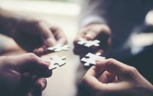 Four individual hands each putting puzzle pieces together