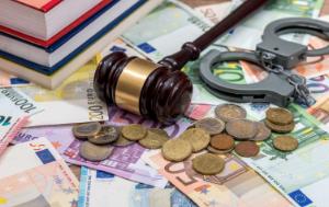 A judge's wooden gavel and a pair of handcuffs rest on euro banknotes and coins, with several law books nearby. The image symbolizes legal issues involving money, such as financial crime, fines, fraud, or justice.