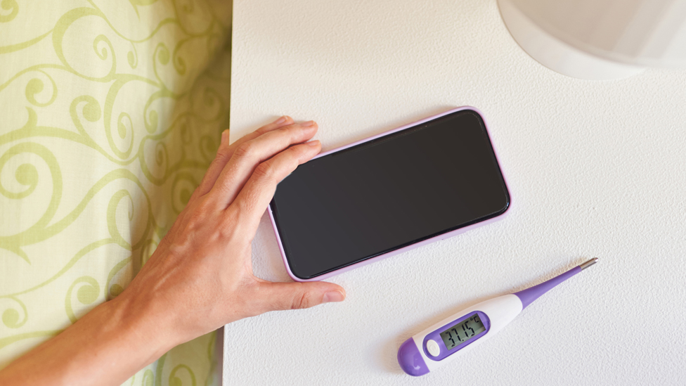 (Quelle: Jose - stock.adobe.com) Smartphone neben dem ein Thermometer liegt