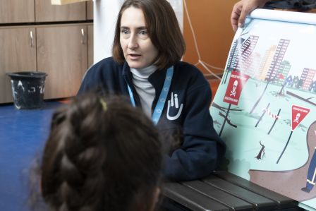 Frau hält ein Schild zur Gefahrenaufklärung in die Höhe vor einer Menschengruppe