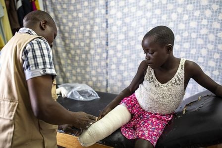 Ein junges Mödchen mit verbundenem Bein-Stumpf wird von einem HI-Experten behandelt.