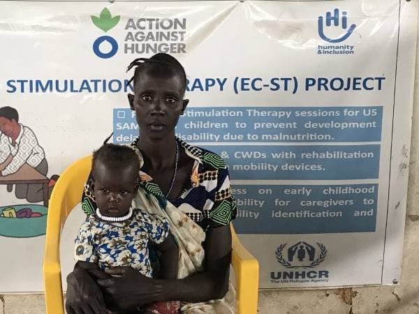 Eine Mutter aus Äthiopien hat ihr unterernährtes Kind auf dem Schoß und schaut ernst in die Kamera.