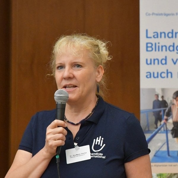 Eine Frau mit blonden Haaren spricht in ein Mikrofon.