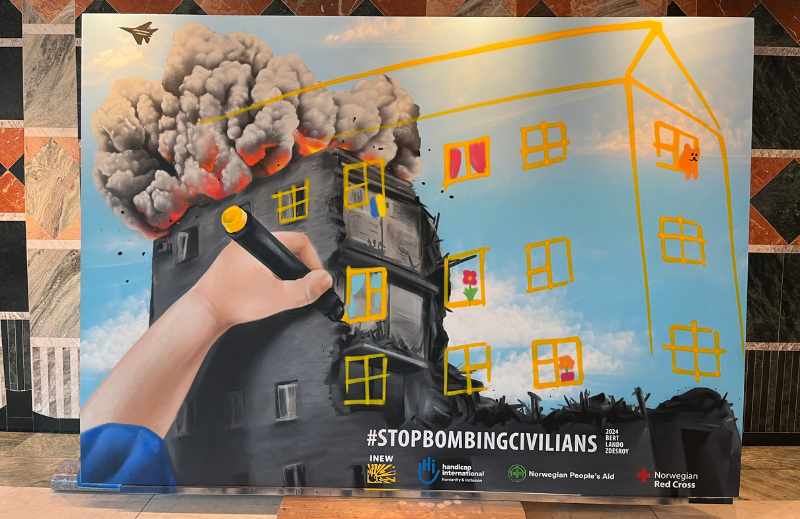 Darstellung von einem zerbomben Haus in der Ukraine. Link unten sieht man einen Kinderarm, der über das Bild der Zerstörung ein neues Haus mit Blumen im Fenster und Teddybären malt. Die Hoffnung symbolisieren sollen.