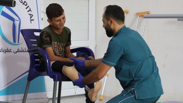 Ein lächelnder Junge bekommt eine Prothese angepasst.