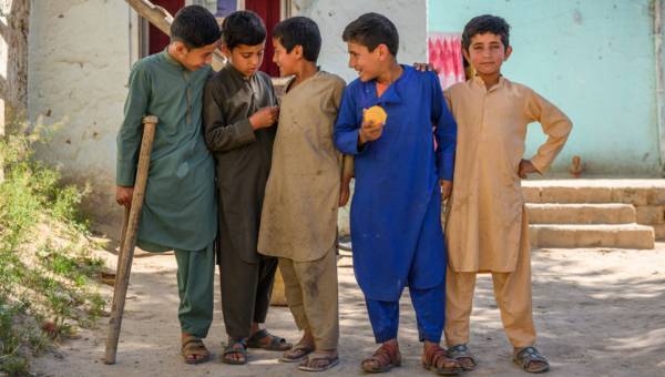 Eine Gruppe Jungen steht zusammen und lacht. Einer von ihnen hat ein amputiertes Bein und eine Unterarm-Krücke.