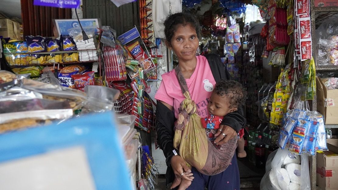 A young woman carries her baby in a shop in the Philippines.