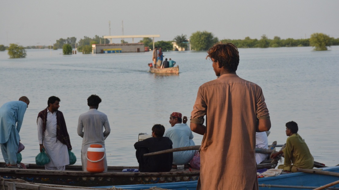 A young man stands in front of the floodwaters.