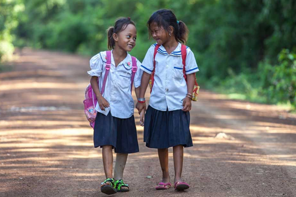 Channa walks to school with a friend in Cambodia.