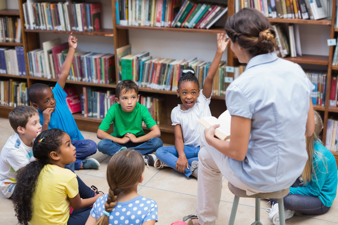 elementary school children reading with a teacher