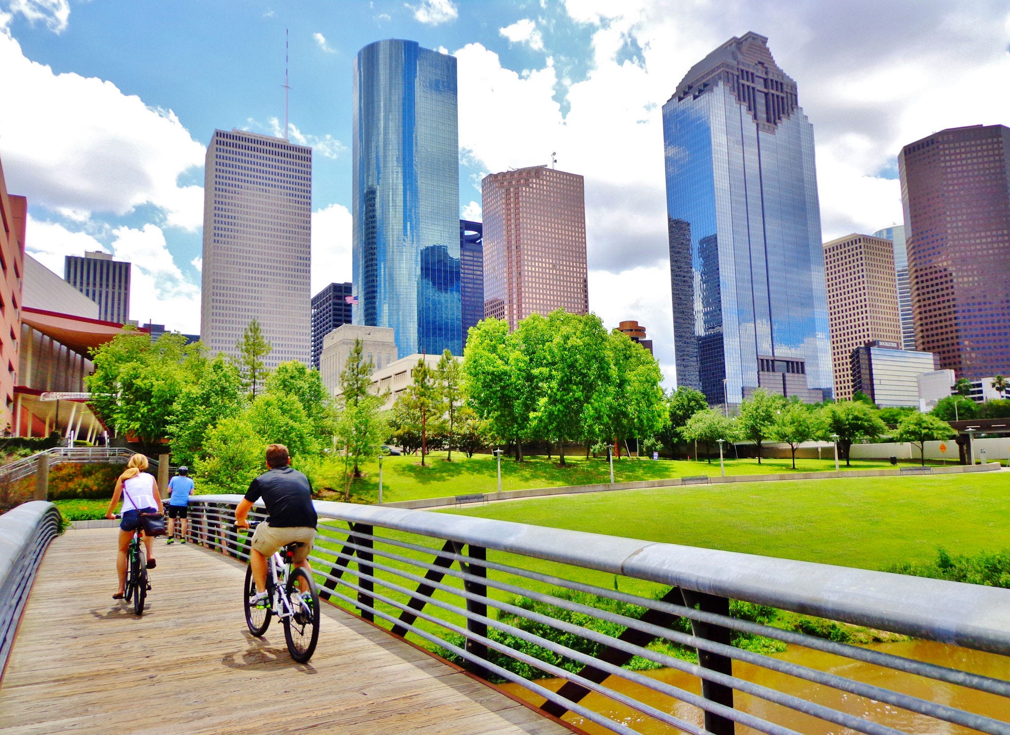 people bicycling along bridge near a city