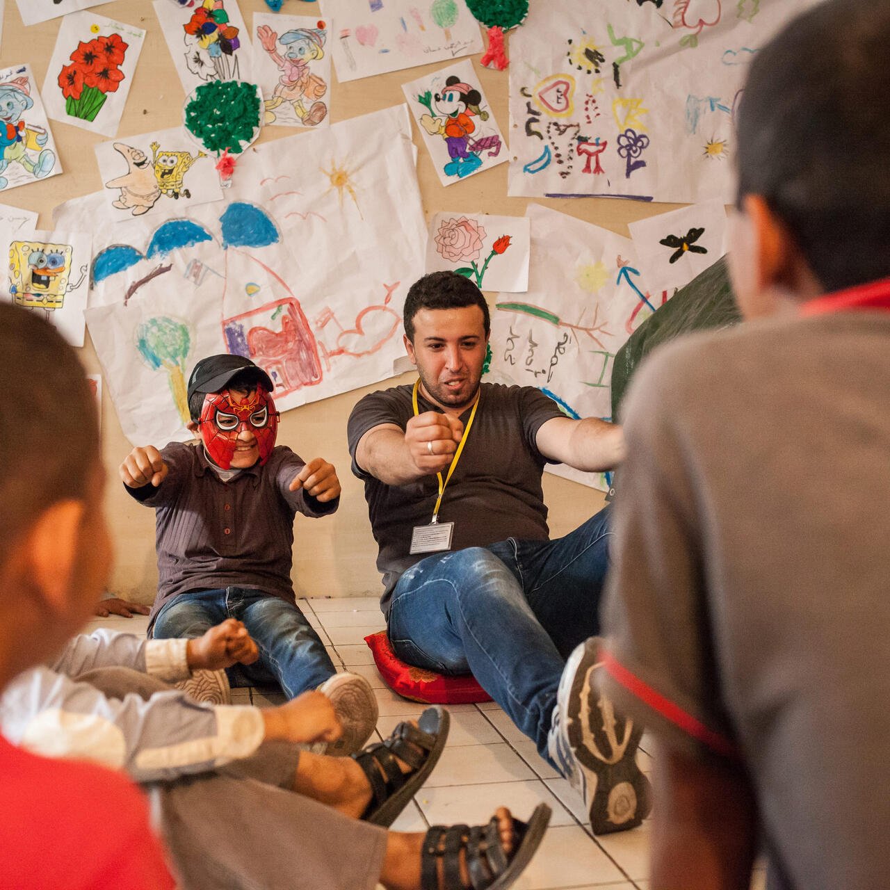 레바논에서, 한남자와스파이더맨마스크를쓴소년이아이들의그림이걸려있는벽앞에서운동을하고있습니다.