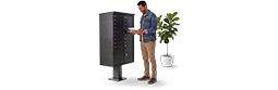 Next to a potted plant, a man checks his mail from a dark community mailbox.