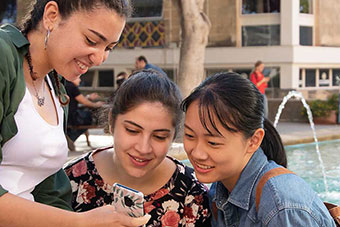 Girls on Quadrangle looking at a smartphone