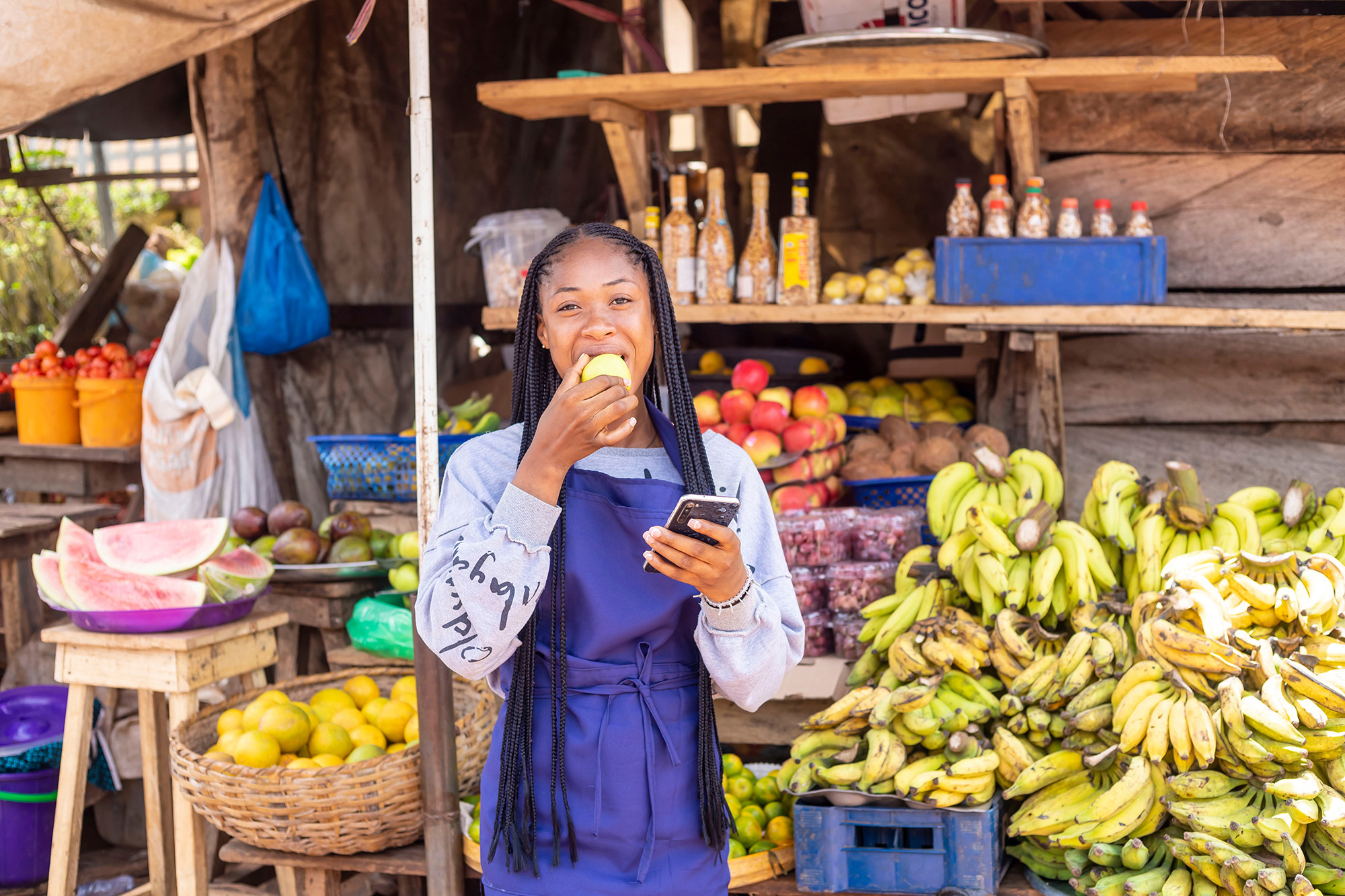Young African businesswoman browsing news online at a local market.