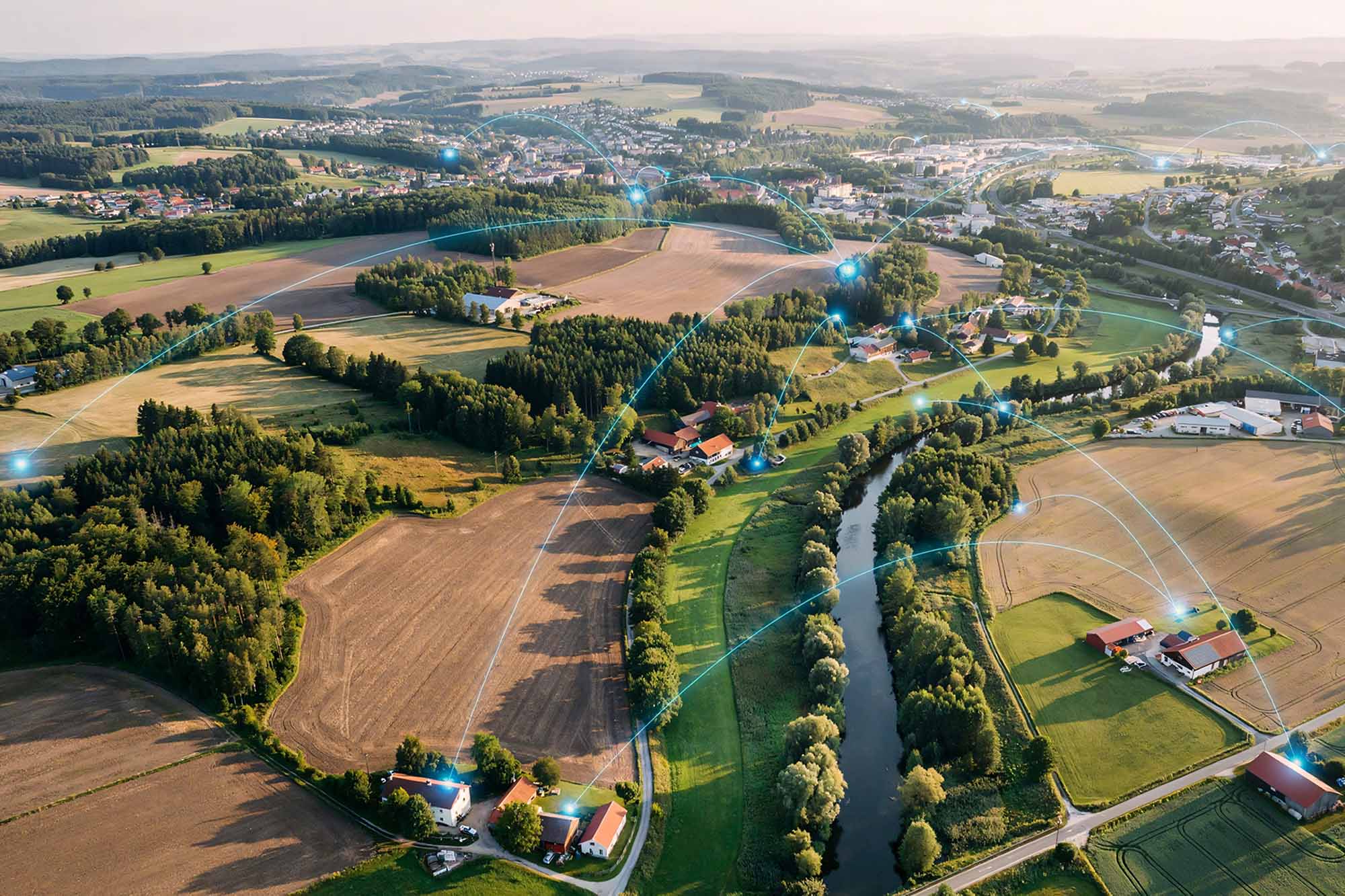 Aerial view of a rural landscape with digital network connections overlaying villages and farms.