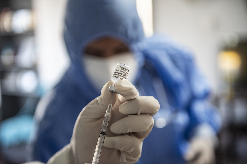 A healthcare worker prepares a COVID-19 vaccine for an elderly resident during a home visit in Peru.