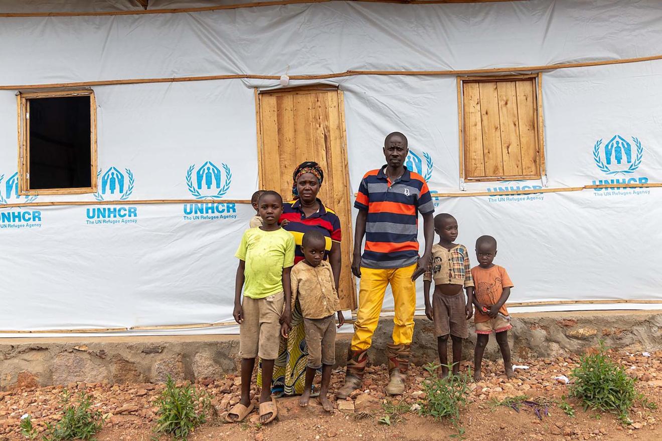 A family standing in front of a shelter built after the floodings in Burundi.