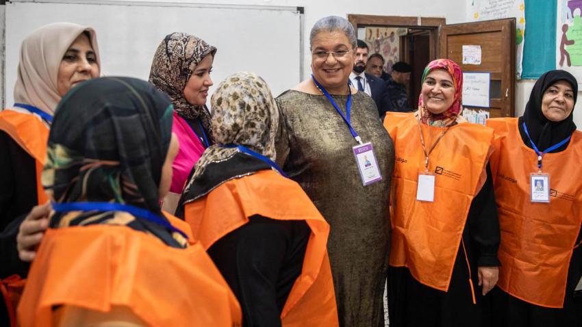 Hanna in a classroom surrounded by women in veils all wearing orange vests
