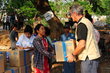 Man in WFP vest hands box of high-energy biscuits to a woman affected by the earthquake in Myanmar