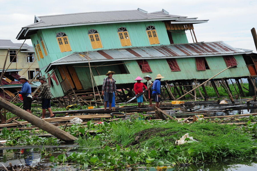 People in hard hats observe a small building tilting sideways after Myanmar earthquake