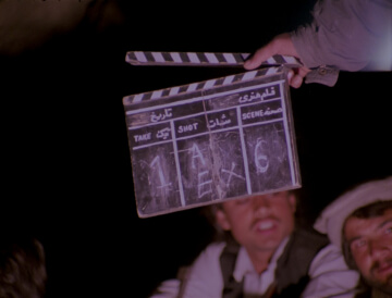 Someone holds a slate covering the face of a man